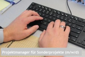 Hände tippen auf Tastatur am Büroarbeitsplatz mit Notizblock