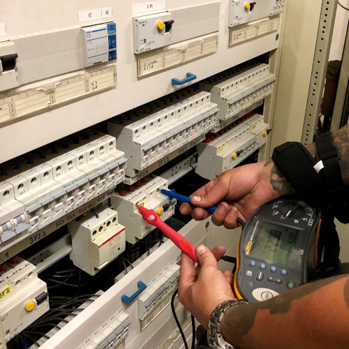 Techniker misst elektrische Werte an einem Schaltschrank mit Messgerät