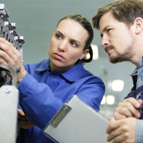 Zwei Mitarbeitende prüfen gemeinsam eine technische Anlage in der Produktion