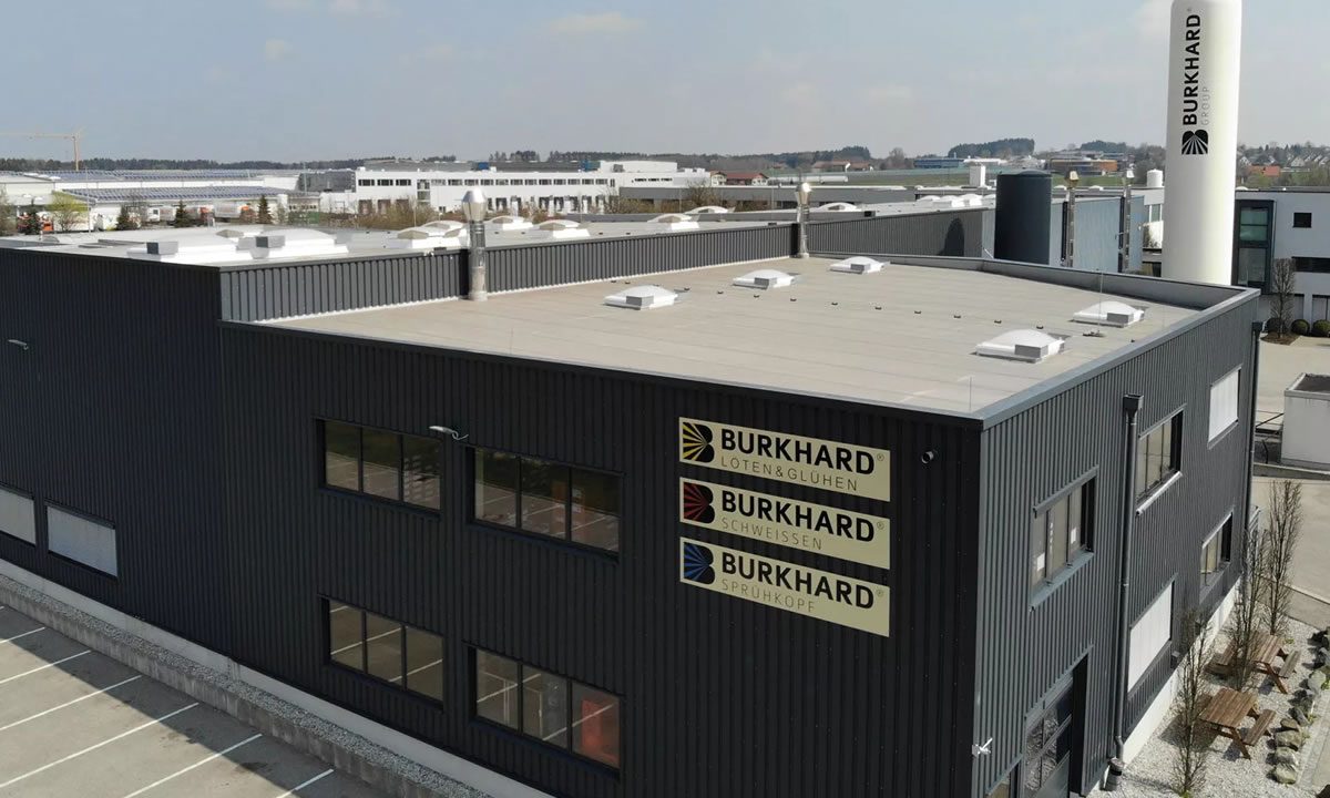 Firmengebäude der Burkhard Group mit Logos für Löten & Glühen, Schweißen und Sprühkopf